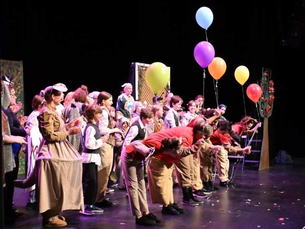 Actors of all ages bowing in front of an audience